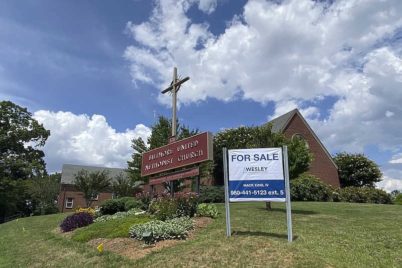 This photo provided by the Rev. Lucy Robbins shows a &quot;For Sale&quot; sign in front of the Biltmore United Methodist Church in Asheville, N.C. in July 2021. Already financially strapped because of shrinking membership and a struggling preschool, the congregation was dealt a crushing blow by the coronavirus. Attendance plummeted, with many staying home or switching to other churches that stayed open the whole time. Gone, too, is the revenue the church formerly got from renting its space for events and meetings. (Rev. Lucy Robbins via AP)