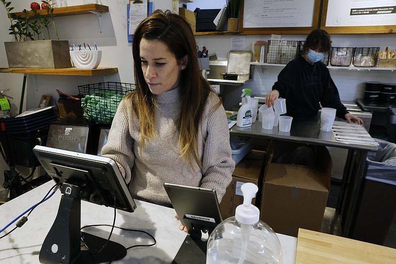 Deena Jalal, owner of plant-based ice cream chain FoMu, works behind the counter in her shop on Tremont Street, Friday, Jan 14, 2022, in Boston. (AP Photo/Michael Dwyer)