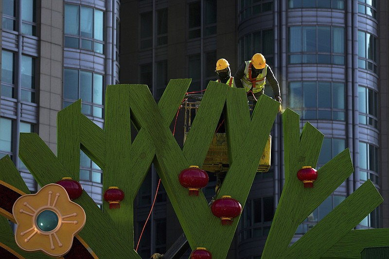Workers color Chinese Lunar New Year decorations near a commercial office building in Beijing on Sunday, Jan. 16, 2022. China&#x2019;s economy expanded by 8.1% in 2021 but Beijing faces pressure to shore up activity after an abrupt slump in the second half as the ruling Communist Party forced its vast real estate industry to cut surging debt. (AP Photo/Andy Wong)