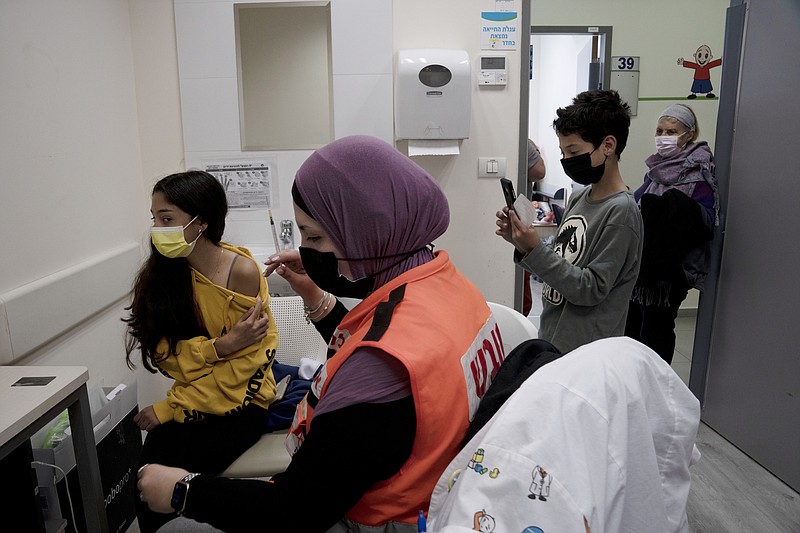 N'amah Yetzhak Abohaikal, a volunteer with the women's unit of United Hatzalah emergency service, prepares administer the COVID-19 vaccine to a teen girl as her brother and grandmother watch, at Clalit Health Services in Mevaseret Zion, Tuesday, Jan. 11, 2022. (AP Photo/Maya Alleruzzo)