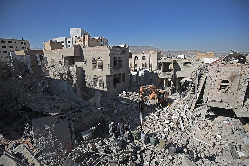 People inspect the wreckage of buildings that were damaged by Saudi-led coalition airstrikes, in Sanaa, Yemen, Tuesday, Jan. 18, 2022. The coalition fighting in Yemen announced it had started a bombing campaign targeting Houthi sites a day after a fatal attack on an oil facility in the capital of the United Arab Emirates claimed by Yemen?s Houthi rebels. It said it also struck a drone operating base in Nabi Shuaib Mountain near Sanaa. (AP Photo/Hani Mohammed)