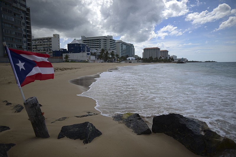 FILE - A Puerto Rican flag flies on an empty beach at Ocean Park, in San Juan, Puerto Rico, Thursday, May 21, 2020.  Puerto Rico&#x2019;s nearly five-year bankruptcy battle was resolved Tuesday, Jan. 18, 2022, after a federal judge signed a plan that slashes the U.S. territory&#x2019;s public debt load as part of a restructuring and allows the government to start repaying creditors. (AP Photo/Carlos Giusti, File)