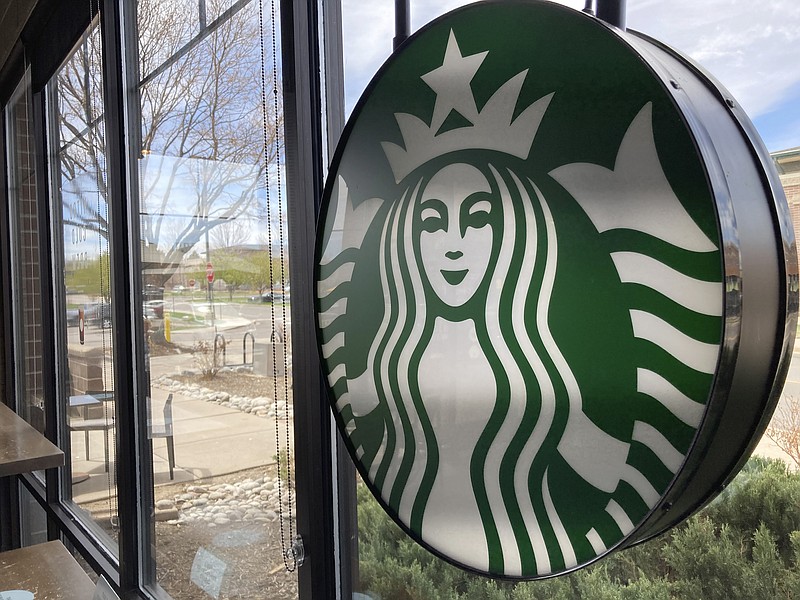 A sign bearing the corporate logo hangs in the window of a Starbucks open only to take-away customers in this photograph taken Monday, April 26, 2021, in southeast Denver.  Starbucks is no longer requiring its U.S. workers to be vaccinated against COVID-19, reversing a policy it announced earlier this month. The Seattle coffee giant says, Wednesday, Jan. 19, 2022,  it's responding to last week&#x2019;s ruling by the U.S. Supreme Court.  (AP Photo/David Zalubowski)