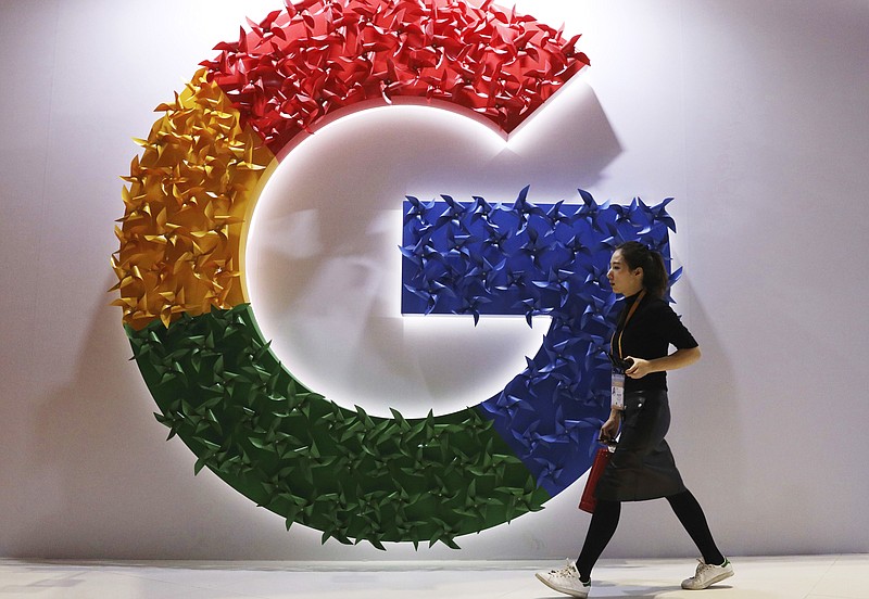 FILE - A woman walks past the logo for Google at the China International Import Expo in Shanghai, Nov. 5, 2018. Online companies would have to ramp up efforts to keep harmful content off their platforms and take other steps to protect users under rules that European Union lawmakers approved Thursday Jan. 20, 2022. (AP Photo/Ng Han Guan, File)