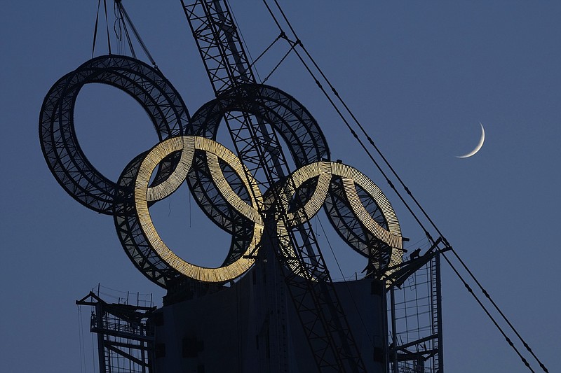 A worker labors to assemble the Olympic Rings onto of a tower on the outskirts of Beijing, China, on Jan. 5. The Beijing Winter Olympics are fraught with potential hazards for major sponsors, who are trying to remain quiet about China's human rights record while protecting at least $1 billion they've paid to the IOC. – Photo by Ng Han Guan of The Associated Press