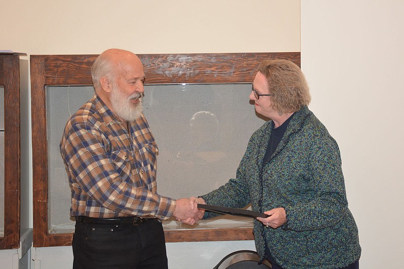 Marc Hayot/Herald-Leader Mayor Judy Nation (right), presents Don Warden, the director of collections of research for the Siloam Springs Museum, a proclamation during the museum board meeting on Thursday. Warden has worked for the museum for 30 years and has even written a book titled &quot;Images of America Siloam Springs&quot; in 2012.