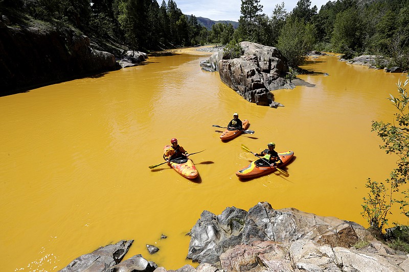 FILE - People kayak in water colored from a mine waste spill at the Animas River near Durango, Colo., on Aug. 6, 2015. Colorado, the U.S. government and a gold mining company have agreed to resolve a longstanding dispute over who&#x2019;s responsible for cleanup at a Superfund site that was established after a massive 2015 spill of hazardous mine waste.  The proposed settlement announced Friday, Jan. 21, 2022, would direct $90 million to cleanup at the Bonita Peak Mining District Superfund site, according to the U.S. Environmental Protection Agency and Denver-based Sunnyside Gold Corp (Jerry McBride/The Durango Herald via AP, File)