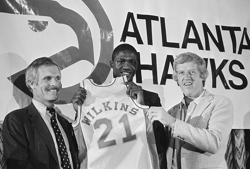 FILE - Dominique Wilkins, all time leading scorer at the University of Georgia, holds his Atlanta Hawks jersey flanked by coach Kevin Loughery, right, and owner Ted Turner on Sept. 4, 1982, in Atlanta. (AP Photo/Joe Holloway, File)