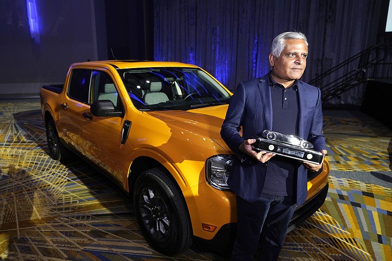 Kumar Galhotra, Ford President of the Americas and International markets group poses next to the Maverick compact pickup, Tuesday, Jan. 11 2022 in Detroit. For the second year in a row, vehicles from Ford Motor Co. took two of the three North American Car, Truck and Utility of the Year awards. The company's Maverick compact pickup won truck of the year, while its Bronco off-road SUV earned the utility of the year. Honda's redesigned Civic compact car won the car of the year. (AP Photo/Carlos Osorio)