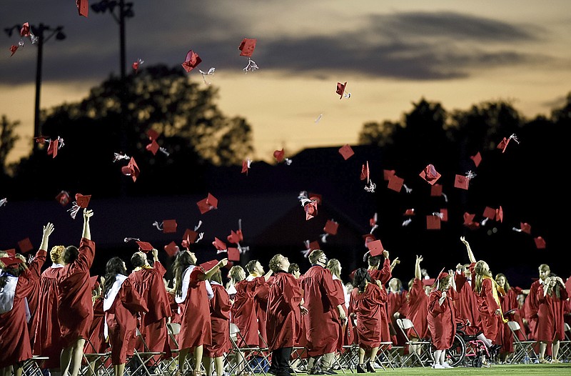 FILE - Red mortarboards fly into the evening sky at Heritage High School's commencement ceremony Friday, July 24, 2020, in Maryville Tenn.  High school graduation rates dipped in at least 20 states after the first full school year disrupted by the pandemic, according to a new analysis by Chalkbeat.  (Scott Keller/The Daily Times via AP, File, File)