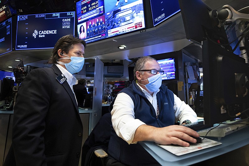 In this photo provided by the New York Stock Exchange, trader Michael Conlon, right, works on the floor, Tuesday, Jan. 25, 2022. Stocks fell sharply on Wall Street Tuesday, continuing a volatile bout of trading that has sent markets swinging between sharp losses and gains as investors gauge several threats. (Allie Joseph/New York Stock Exchange via AP)