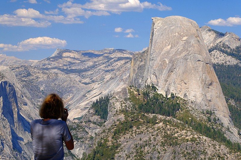 A visitor snaps photos of Half Dome from Washburn Point in Yosemite National Park on Aug. 4, 2021. The peak of Half Dome is over 8,000 feet above sea level. (Mark Hume/Chicago Tribune/TNS)