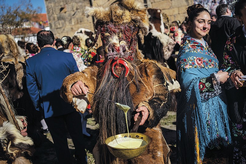 A man dressed as a wild animal or &quot;Carantona&quot; offers sweets as part of the &quot;Las Carantonas&quot; festival in Acehuche, southeast Spain, Thursday, Jan. 20, 2022. With roots in pagan traditions of fertility that were incorporated into religious symbolism, the ancient festival currently marks Acehuche's patron, Saint Sebastian, whom the Catholic tradition considers a martyr of the early anti-Christian Romans. After the 2021 edition was canceled amid a strong surge in coronavirus cases, the festival went ahead in late January this year and under strict mask-wearing rules despite record numbers of infections across Spain fuelled by an ultra-contagion virus variant.(AP Photo/Bernat Armangue)