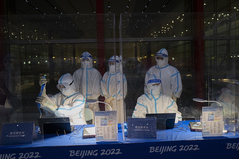 Olympic workers in hazmat suits work at a credential validation desk at the Beijing Capital International Airport ahead of the 2022 Winter Olympics in Beijing, Monday. Athletes and others headed to the Olympics face a multitude of COVID-19 testing hurdles as organizers seek to catch any infections early and keep the virus at bay. – Photo by Jae C. Hong of The Associated Press