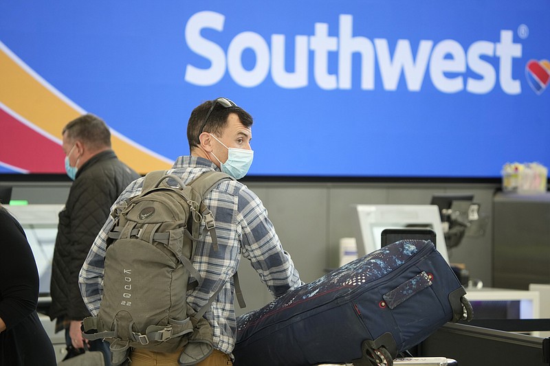 Passenger queues up to check in at the counter for Southwest Airlines Monday, Jan. 3, 2022, in the main terminal of Denver International Airport in Denver. (AP Photo/David Zalubowski)