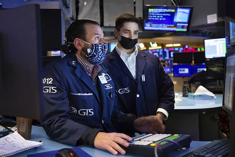 In this photo provided by the New York Stock Exchange, specialist Michael Pistillo, left, works with a colleague at his post on the floor, Friday, Jan. 28, 2022. Stocks rose in afternoon trading on Wall Street Friday, potentially trimming losses for some of the major indexes this week. (Allie Joseph/New York Stock Exchange via AP)