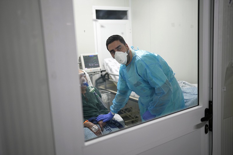 Nurse Filipe Orfao checks on a COVID-19 patient at the respiratory diseases unit of Lisbon's main Santa Maria Hospital, Friday, Jan. 21, 2022. Sunday?s election for a new parliament and government in Portugal is providing a stage for voters to air old grievances. The country?s two main parties, the center-left Socialists and the center-right Social Democrats, have alternated in power for decades, but Portugal's problems haven't changed much. (AP Photo/Armando Franca)