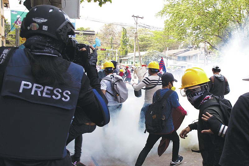 A photographer wearing a protective vest with a 'press' sign at the back films an anti-military government protest being dispersed with tear gas by security forces in Sanchaung township in Yangon, Myanmar on March 3, 2021. Since Myanmar's military dismissed the results of democratic elections and seized power on Feb. 1, 2021, peaceful nationwide protests and violent crackdowns by security forces have spiraled into a nationwide humanitarian crisis. (AP Photo)