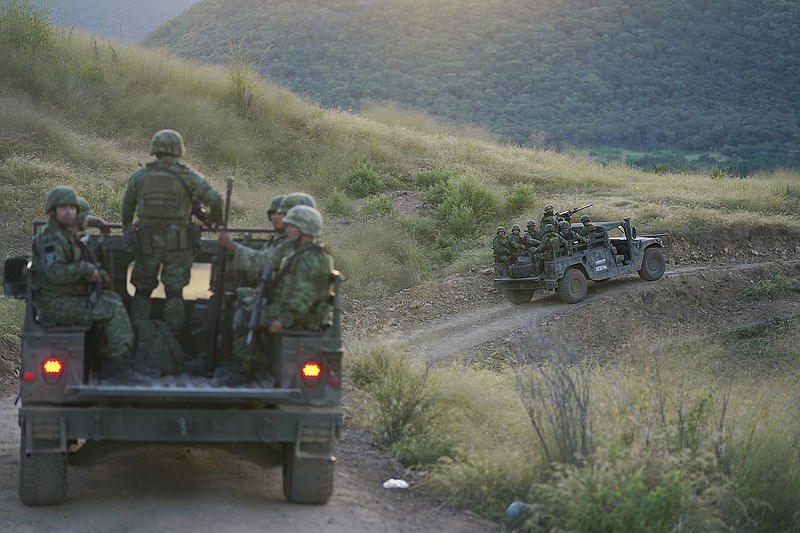 FILE - Soldiers patrol near the hamlet Plaza Vieja in the Michoacan state of Mexico, Oct. 28, 2021. The self-defense movement in the nearby town of Tepalcatepec, said improvised land mines severely damaged an army armored car on Saturday, Jan. 29, 2022.  In the war raging between drug cartels in western Mexico, gangs have begun using improvised explosive devices (IEDs) on roads to disable army vehicles. (AP Photo/Eduardo Verdugo, File)