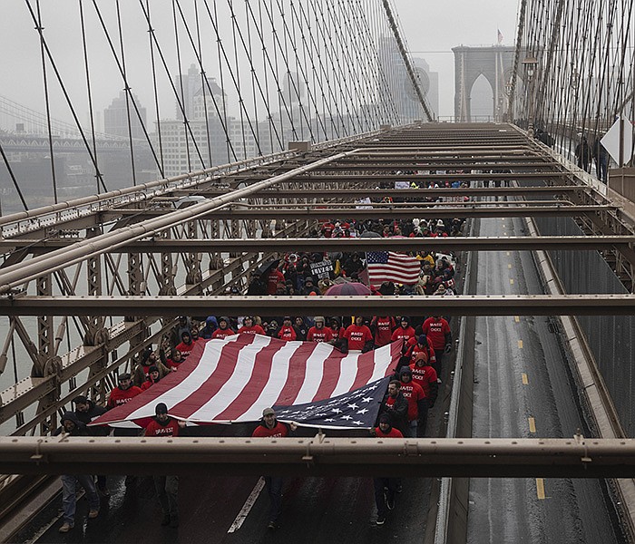 People carrying a large American flag march on Brooklyn Bridge during an anti-vaccine mandate protest ahead of possible termination of New York City employees due to their vaccination status, Monday, Feb. 7, 2022, in New York. (AP Photo/Yuki Iwamura)