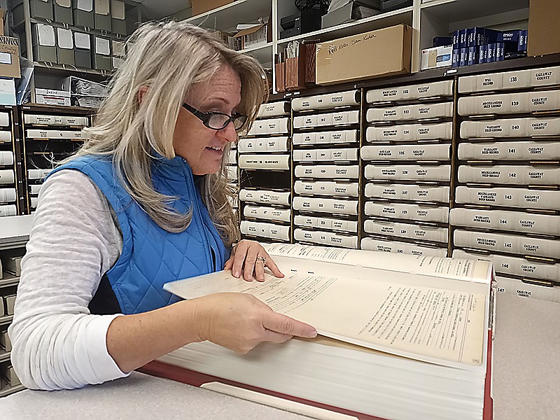 County Recorder of Deeds Christine Kleindienst flips through one of the over 200 books of historical deeds kept in her office. (Michael Shine/Fulton Sun)