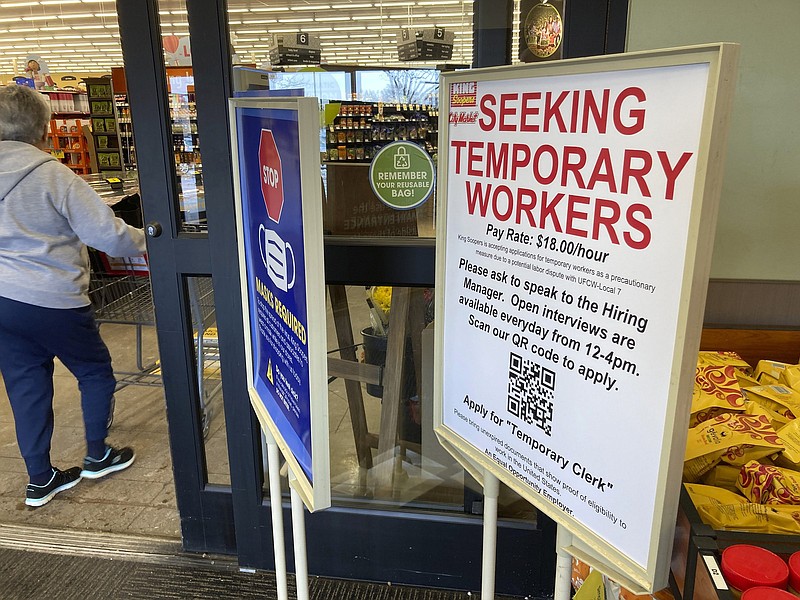 A sign advertising the need for temporary workers stands next to the entrance of a King Soopers grocery store Thursday, Jan. 6, 2022, in southeast Denver. The union representing King Soopers workers in Colorado is calling for a strike against the Kroger-owned grocery chain that could start as early as Sunday, Jan. 9, a day after its contracts end with stores in the Denver area and Colorado Springs, Colo. The strike would be the first against King Soopers since 1996. (AP Photo/David ZalubowskI)
