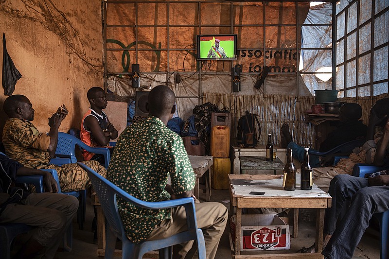 People gather in a bar to watch the presidential inauguration of Junta leader Lt. Col. Paul Henri Sandaogo Damiba during his swearing-in ceremony broadcast on national television on Wednesday Feb. 16, 2022 in Ouagadougou, Burkina Faso. The inauguration ceremony, not open to the general public, was held at the constitutional court. (AP Photo/Sophie Garcia)