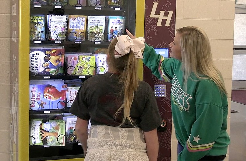 Lake Hamilton Elementary School second grade counselor Allison Spraggins shows a student how to use the school’s new book vending machine Friday morning. - Photo by Tyler Wann of The Sentinel-Record