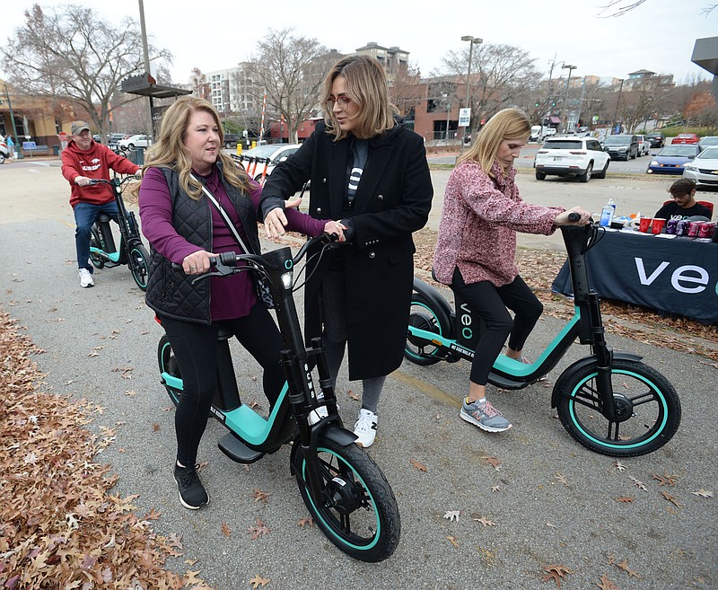 Carol Antunez (center), policy and partnerships manager for VeoRide, helps to acquaint Jackie Moore (left) of Russellville on Dec. 4 with the controls of a sit-down electric scooter before she rides with friends along the Razorback Greenway from Dickson Street in Fayetteville. The City Council got an update Tuesday on scooter use in the city. (File photo/NWA Democrat-Gazette/Andy Shupe)