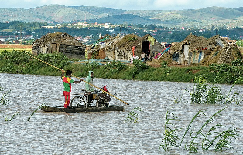 FILE - Residents cross flooded fields following Cyclone Enawo in Madagascar's capital Antananarivo, on March 9, 2017. Africa has contributed relatively little to the planet's greenhouse gas emissions but has suffered some of the heaviest impacts of climate change and the reverberations of human-caused global warming will only get worse, according to a new United Nations report released Feb. 28, 2022. (AP Photo/Alexander Joe, File)