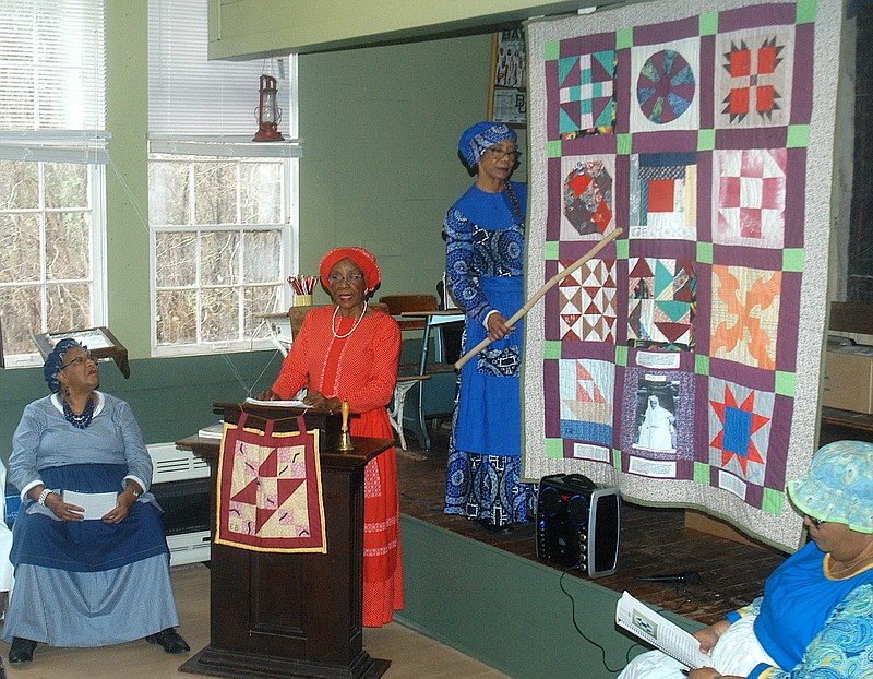 Flo Stephenson points to a quilt that the Pleasant Hill Quilters have made to explain its secret messages for fleeing slaves. With her to sing and explain even further are, from left, LaWanda Warren, Ether Blaylock and Oteria McDaniel. (Photo by Neil Abeles)