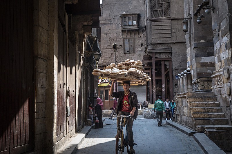 A cyclist balances a bread board on his head as he rides in Cairo on March 31, 2018. MUST CREDIT: Bloomberg photo by Sima Diab.
