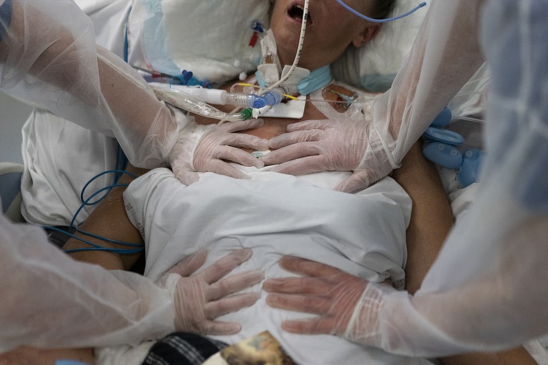 FILE - Nurses perform timed breathing exercises on a COVID-19 patient on a ventilator in the COVID-19 intensive care unit at the la Timone hospital in Marseille, southern France, Friday, Dec. 31, 2021. The official global death toll from COVID-19 is on the verge of eclipsing 6 million &#x2014; underscoring that the pandemic, now in its third year, is far from over. (AP Photo/Daniel Cole, File)