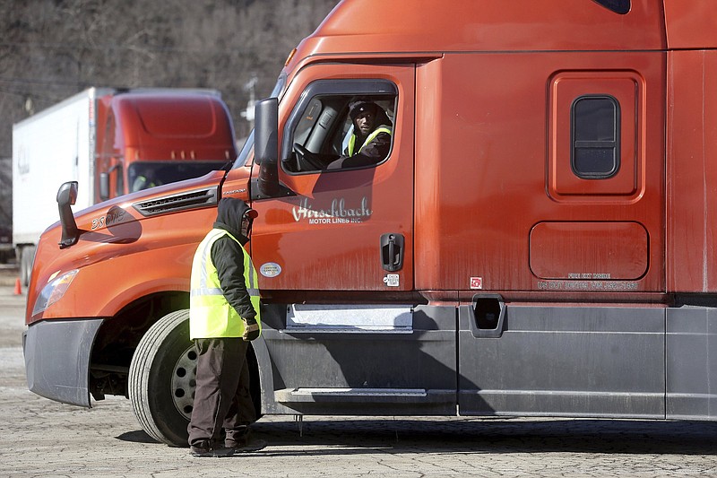 In this Wednesday, Feb. 23, 2022, photo, Marty Funke, an instructor at Hirschbach Motor Lines, watches as Mohammed Keita, of Ramsey, Minn., maneuvers his semi-tractor trailer in a parking lot during a commercial driver's license training program in Dubuque, Iowa. (Jessica Reilly/Telegraph Herald via AP)