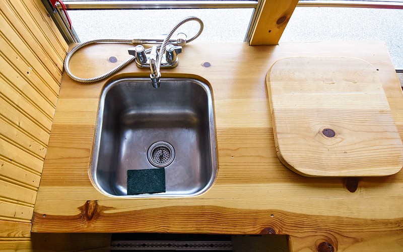 (India Garrish/News Tribune) In a skoolie, the more space can be optimized, the better. Dave Kohler made a cutting board to go over his small kitchenette sink to create more counter space, which is shown Sept. 20, 2021. (1/2 collage)