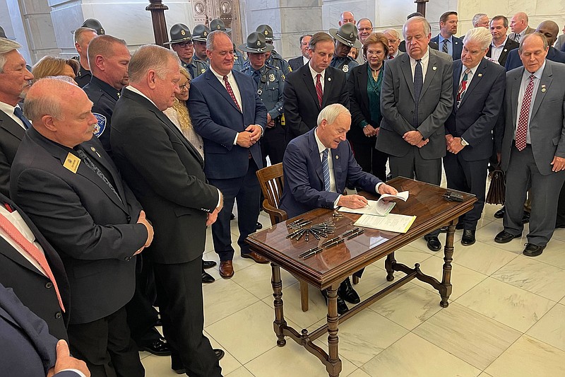 Arkansas Gov. Asa Hutchinson signs into law legislation giving law enforcement officers a one-time payment at the state Capitol in Little Rock, Ark., Tuesday, March 8, 2022. Hutchinson signed the legislation shortly after lawmakers wrapped up this year's session. (AP Photo/Andrew Demillo)
