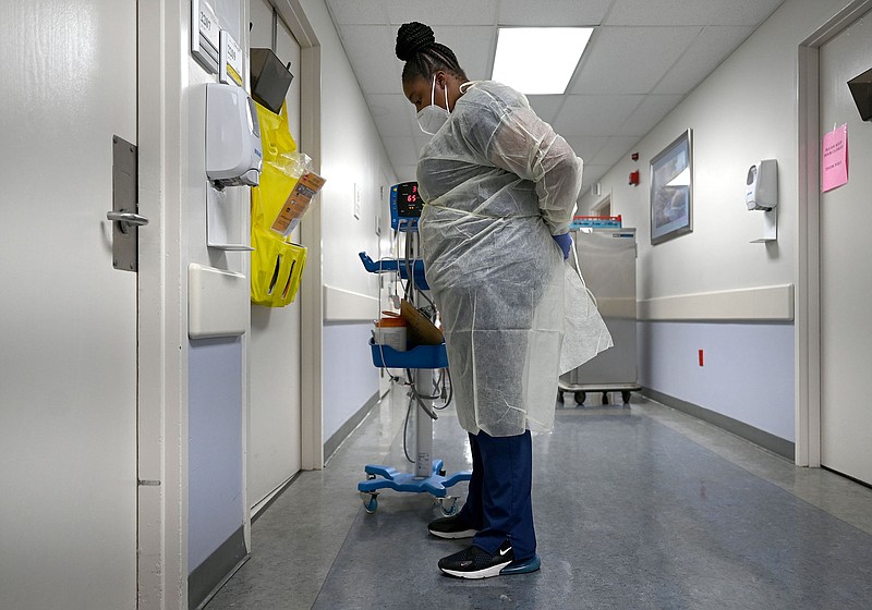 Sharaina Smiley, a Patient Care Technician at Jefferson Regional Medical Center in Pine Bluff, puts on PPE before entering a patient's room in the covid ward of the hospital on Friday, Feb. 18, 2022. (Arkansas Democrat-Gazette/Stephen Swofford)