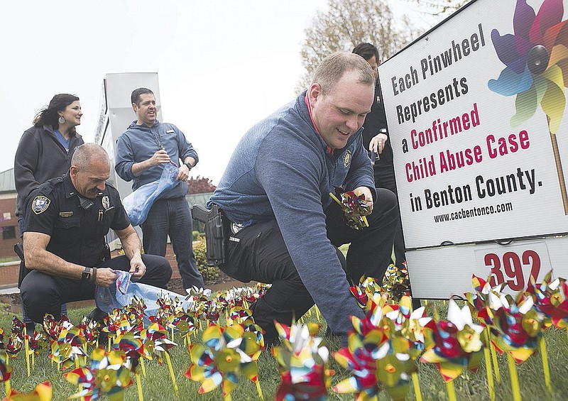 Det. Andrew Corbett (center right)†places pinwheels into the ground, Friday, April 3, 2020 at the Bentonville Police Department in Bentonville. Check out nwaonline.com/200404Daily/ for todayís photo gallery.
(NWA Democrat-Gazette/Charlie Kaijo)

April is child abuse awareness month in Benton County. All law enforcement and child protective agencies that work child abuse cases in Benton County placed pinwheels to signify the confirmed child abuse cases from the previous year. 19 agencies participated, and each agency placed 392 pinwheels at their locations.