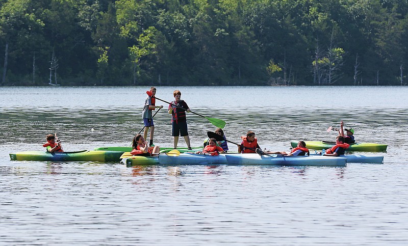 Orland Long, center, and Porter Schaefer, far, stand on paddle boards among a group of kayakers Wednesday morning, April 6, 2022, at Binder Lake. The Jefferson City Parks, Recreation and Forestry Department hosted a camp for kids in grades 3-5, allowing them to explore the lake on kayaks, canoes and paddle boards. (Jason Strickland/News Tribune photo)