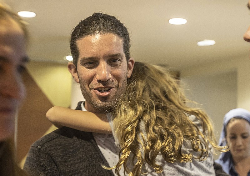 Town of Surfside, Fla., newly elected Mayor Shlomo Dazinger holds his daughter as he celebrates with supporters after defeating incumbent Mayor Charles W. Burkett, during an election night at the Town Hall, on Tuesday March 15, 2022.  (Pedro Portal/Miami Herald via AP)