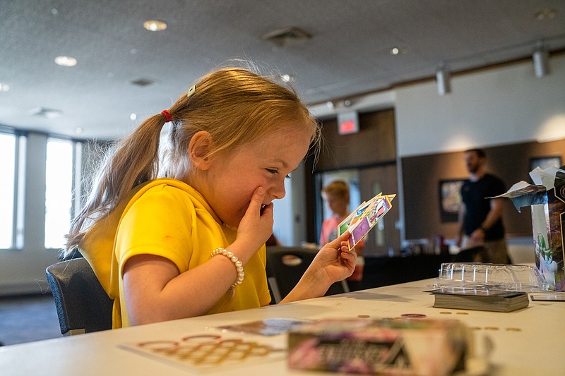 Adalynn Walters giggles as she draws her first hand of Pokemon cards Saturday, March 19, 2022, during a learn-to-play event at the Missouri River Regional Library in Jefferson City. The event was held by Proud Pancake Company — an online card shop. (Ethan Weston/News Tribune photo)