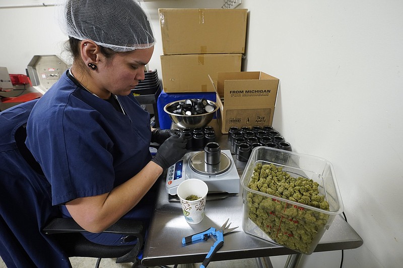 Jessica Owl, weighs True North Collective recreational marijuana, during packaging in Jackson, Mich., earlier this monthcq. Wednesday, March 2, 2022. Over the past few years, Jonny Griffis has invested millions of dollars in his legal marijuana farm in northern Michigan, which produces extracts to be used in things like gummy bears and vape oils. But now that farm ? like many other licensed grows in states that have legalized marijuana ? faces an existential threat: high-inducing cannabis compounds derived not from the heavily regulated and taxed legal marijuana industry, but from a chemical process involving little-regulated, cheaply grown hemp. (AP Photo/Paul Sancya)