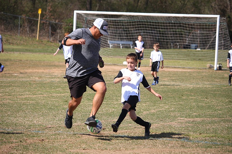 Hot Springs Soccer Association coach Jjesus Anaya goes into a challenge against Hayzten Anaya while players and parents scrimmaged at the Munro Soccer Complex Saturday morning. The HSSA made improvements to the complex and has seen a growth in players from surrounding areas. - Photo by Krishnan Collins of The Sentinel-Record