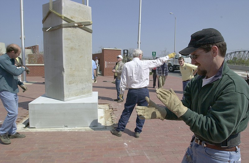 Artist Joseph Buchanan (right) applauds as Ken McConnell (left) and co-workers with McConnell Heavy Hauling of Little Rock install a 13,000-pound slab of marble from Batesville on April 4, 2002, on the Statehouse Convention Center plaza at Markham and Scott streets in downtown Little Rock. (Democrat-Gazette file photo)