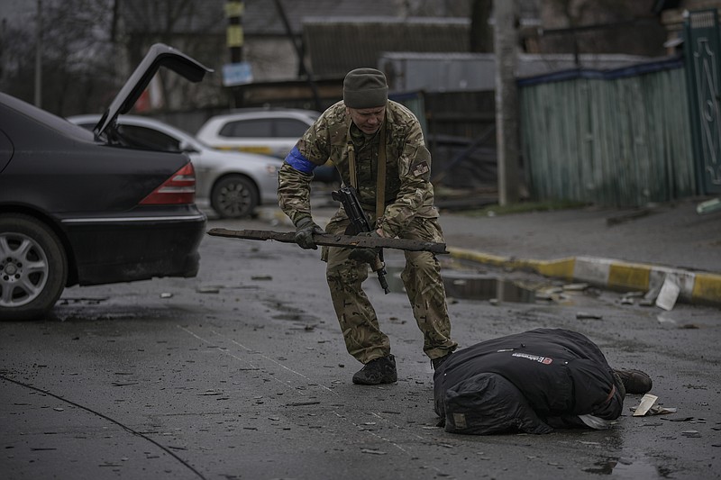 A Ukrainian serviceman checks the dead body of a civilian for booby traps in the formerly Russian-occupied Kyiv suburb of Bucha, Ukraine, Saturday, April 2, 2022. As Russian forces pull back from Ukraine's capital region, retreating troops are creating a "catastrophic" situation for civilians by leaving mines around homes, abandoned equipment and "even the bodies of those killed," President Volodymyr Zelenskyy warned Saturday.(AP Photo/Vadim Ghirda)