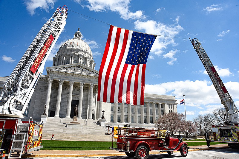 The United States flag is hoisted by two firetrucks Tuesday, April 5, 2022, during Firefighter Day in front of the Missouri Capitol in Jefferson City. (Julie Smith/For the FULTON SUN)