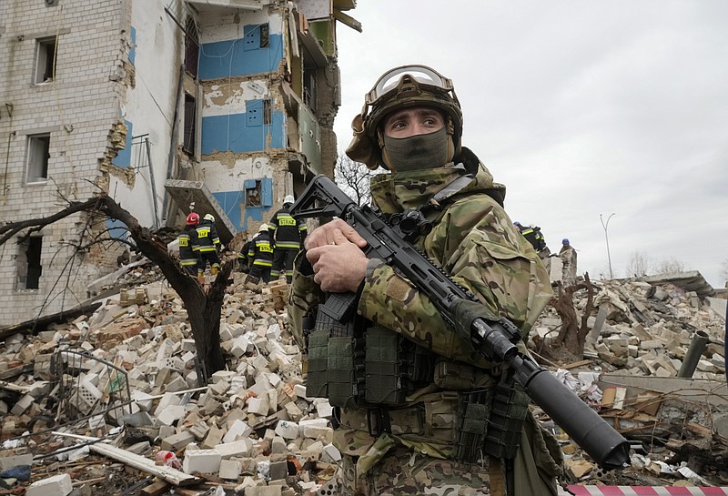 A Ukrainian soldier stands against the background of an apartment house ruined in the Russian shelling in Borodyanka, Ukraine, Wednesday, Apr. 6, 2022. (AP Photo/Efrem Lukatsky)