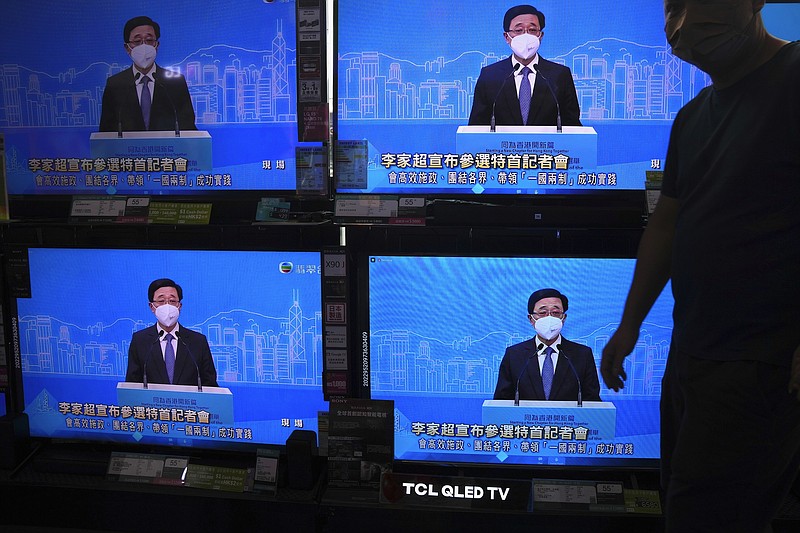 The TV screens show former Hong Kong Chief Secretary John Lee speaks during an online press conference to announce his candidacy for the Election of the Hong Kong chief executive, in Hong Kong, Saturday, April 9, 2022. (AP Photo/Kin Cheung)