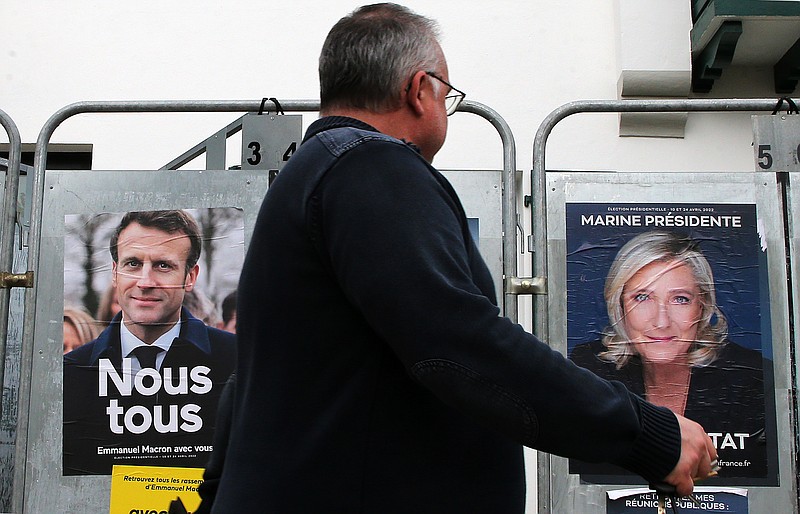 A man walks past presidential campaign posters of french president Emmanuel Macron and centrist candidate for reelection and french far-right presidential candidate Marine Le Pen in Anglet, southwestern France, Wednesday, April 8, 2022. (AP Photo/Bob Edme)
