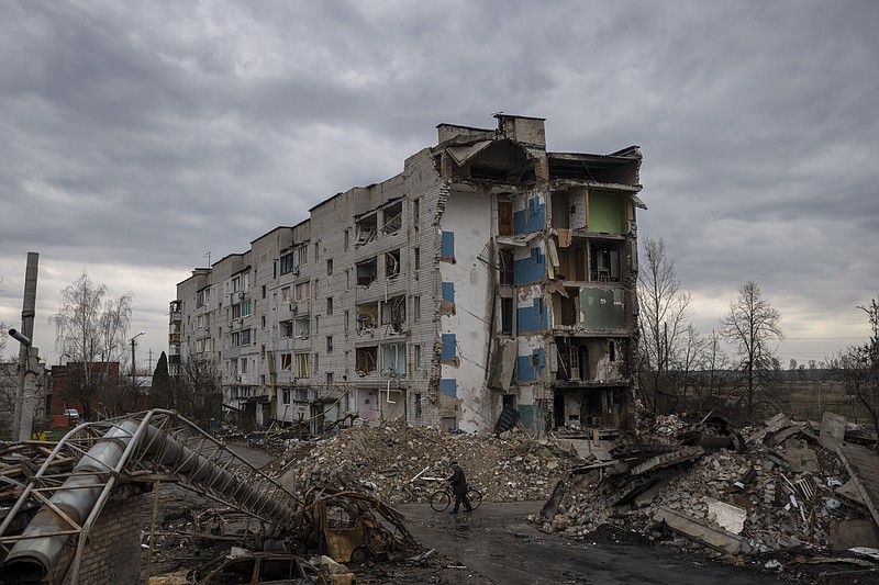 A man with a bicycle walks in front of a destroyed apartment building in the town of Borodyanka, Ukraine, on Saturday, April 9, 2022. Russian troops occupied the town of Borodyanka for weeks. Several apartment buildings were destroyed during fighting between the Russian troops and the Ukrainian forces in the town around 40 miles northwest of Kiev. (AP Photo/Petros Giannakouris)